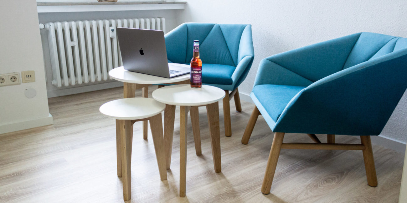 Ecke zum Arbeiten mit blauen Sesseln, kleinen Tischchen und einer Flasche Bionade